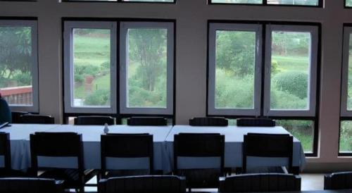 a room with a table and chairs and windows at New Dakshinkali Village Resort in Kathmandu