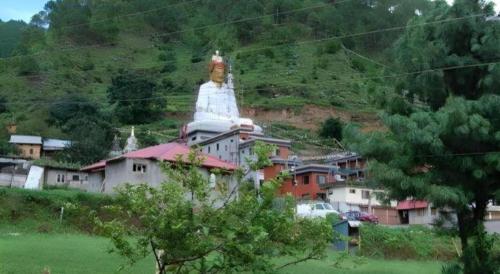 a large statue sitting on top of a hill with houses at New Dakshinkali Village Resort in Kathmandu