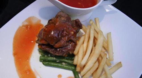 a plate of food with a steak and french fries at Amantis Hotel in Demak