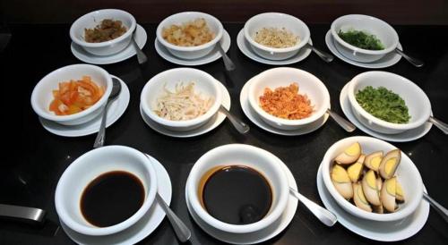 a table with bowls of food and cups of coffee at Amantis Hotel in Demak