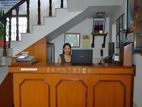 una mujer sentada en un escritorio con una computadora portátil en Hotel Norbu Sangpo, en Katmandú