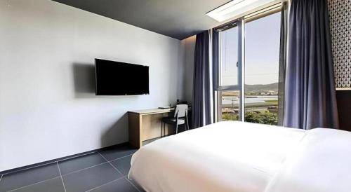 a hotel room with a bed and a television at Gimhae Perfect Hotel in Gimhae