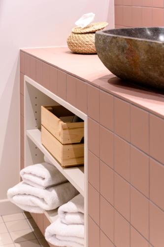 a bathroom with pink tile and a counter with towels at Hof Ter Beuke in Bruges