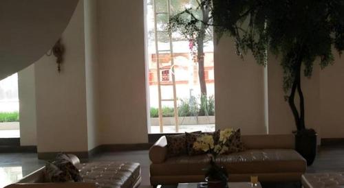 a living room with a couch and a large window at Kenari Tower Hotel in Makassar