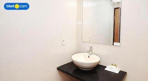 a bathroom with a white sink and a mirror at Kenari Tower Hotel in Makassar