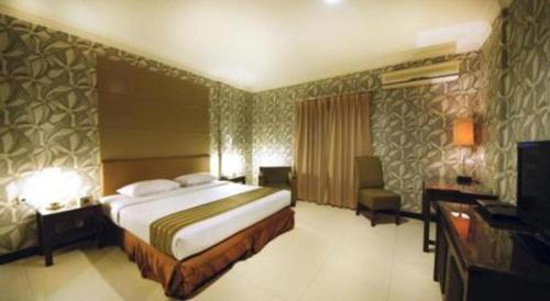 a bedroom with a bed and a desk and a television at Tematik Hotel Pluit in Jakarta