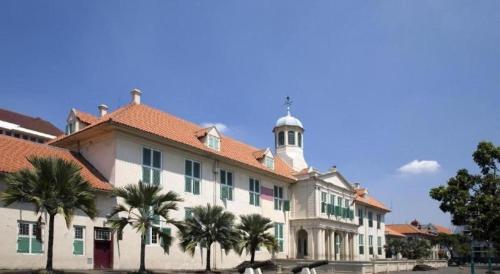 a large building with palm trees in front of it at Tematik Hotel Pluit in Jakarta