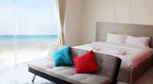 a bedroom with a bed and a couch with colorful pillows at Red Z The Ocean in Phetchaburi