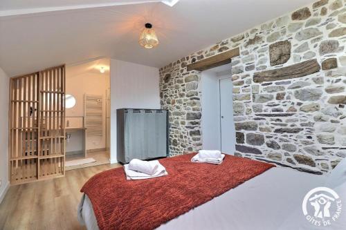 a room with a stone wall and a bed with towels at Le refuge enchante in Paimpont