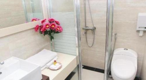 a bathroom with a toilet and a vase of flowers at Plaza Hotel Tegal in Tegal