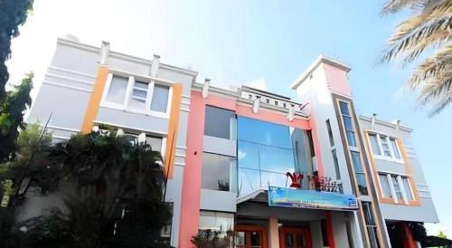 a white and pink building with a window at Plaza Hotel Tegal in Tegal