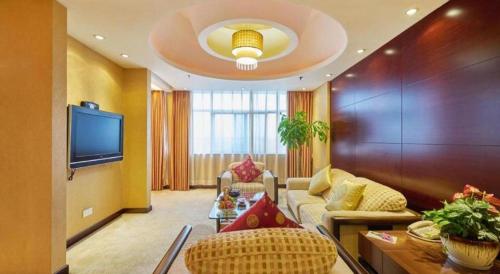 a living room with a couch and a tv at Huangshan International Hotel in Huangshan