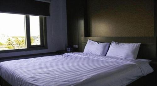 a bedroom with a large white bed with a window at Hotel D' CaLia Tarakan in Tarakan