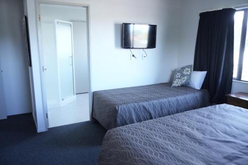 a hotel room with two beds and a mirror at Accommodation Gateway Motel in Palmerston North