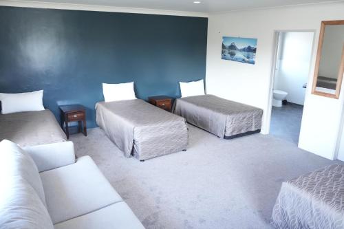 a room with three beds and a couch at Accommodation Gateway Motel in Palmerston North