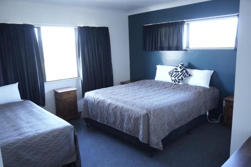 a hotel room with two beds and two windows at Accommodation Gateway Motel in Palmerston North