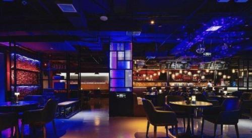 a bar with blue lighting and tables and chairs at NH Shijiazhuang Financial Center in Shijiazhuang