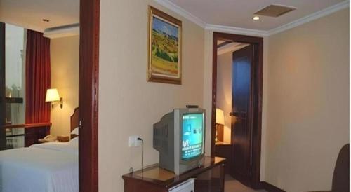 a hotel room with a tv and a bed at Out Sky Hotel in Huizhou