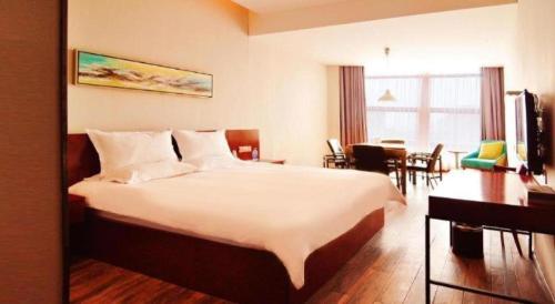 a hotel room with a large bed and a dining room at Hangzhou Berman Hotel in Hangzhou