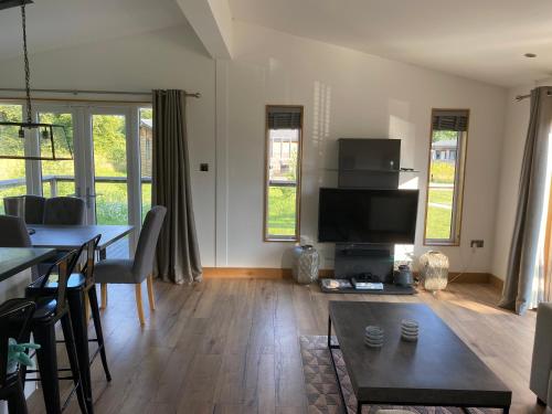 a living room with a dining table and a television at Contemporary 3 bed luxury Spa lodge with hot tub in Bury Saint Edmunds