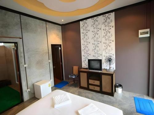 a room with a bed and a tv on a wall at Pilton Resort in Prachuap Khiri Khan