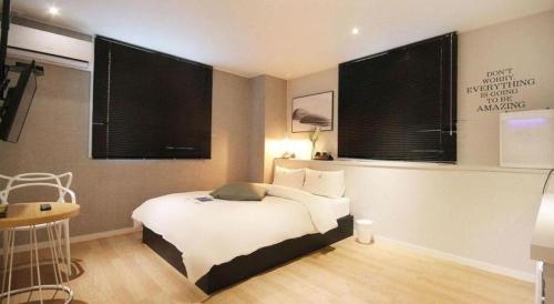 a bedroom with a white bed with two windows at Hotel Yam ANDONG in Andong