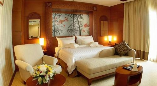 a hotel room with a bed and two chairs at Labersa Grand Hotel &Convention Center in Pekanbaru