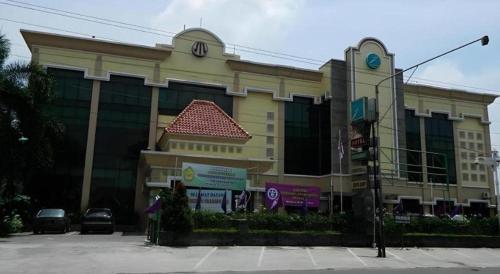 a building with a car parked in front of it at Larisae Setia Kawan Hotel in Solo