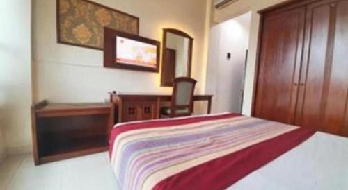 a bedroom with a bed and a desk and a chair at Larisae Setia Kawan Hotel in Solo