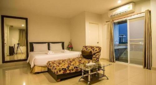 a bedroom with a bed and a chair and a window at At Home at Udon in Udon Thani