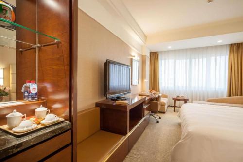 a hotel room with a bed and a television at Best Western Plus Fuzhou Fortune Hotel in Fuzhou