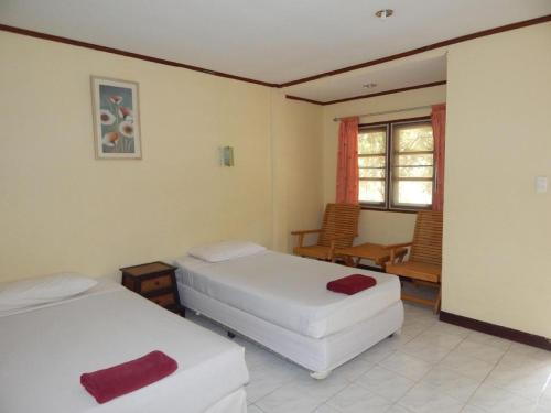 a bedroom with two beds and a chair and a window at Jinta Hotel Nathon Beach in Chaweng