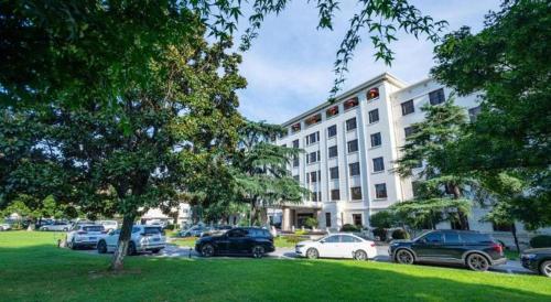 a large building with cars parked in a parking lot at Jin Jiang Nanjing Hotel in Nanjing