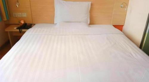 a large white bed in a room with a telephone at 7 Days Inn Hohhot Hailiang Xinhua Square Metro Station in Hohhot