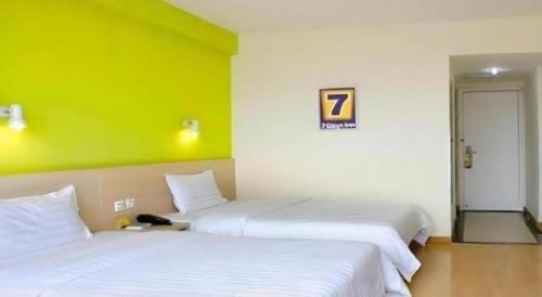 two beds in a room with a green wall at 7 Days Inn Hohhot Hailiang Xinhua Square Metro Station in Hohhot
