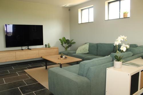 a living room with a blue couch and a tv at Green Bliss in Wervik