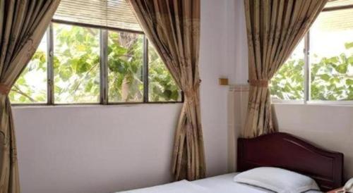 a bedroom with a bed and two windows at Quang Sang Hotel Can Tho in Can Tho