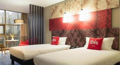 a hotel room with two beds with red pillows at ibis xian North Second Ring Weiyang Rd Hotel in Xi'an