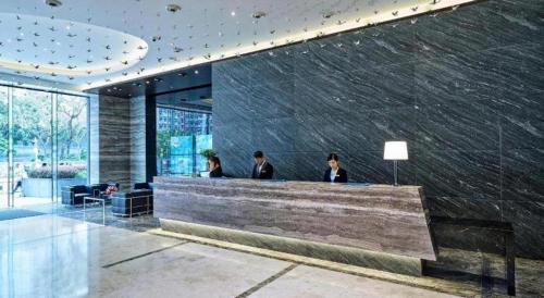 three people sitting at a counter in a lobby at Hotel COZi·Wetland in Hong Kong