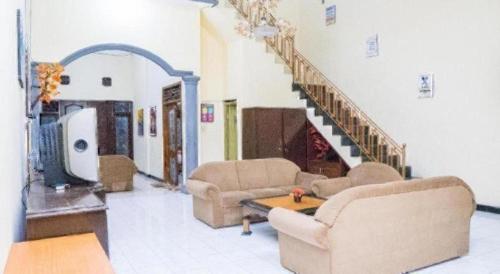 a living room with two couches and a staircase at OYO 643 Al Thalib 8 Syariah in Malang