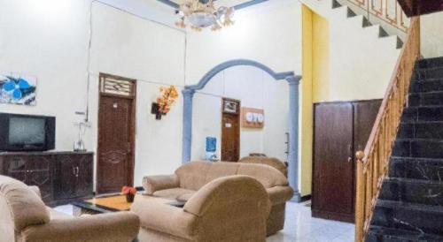 a living room with couches and a tv and stairs at OYO 643 Al Thalib 8 Syariah in Malang