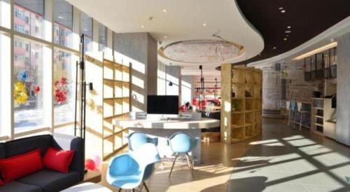 a living room with a couch and a desk and chairs at Ibis Harbin Normal University in Harbin
