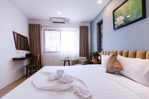 a bedroom with a white bed with a towel on it at Gardenia Hue Hotel in Hue