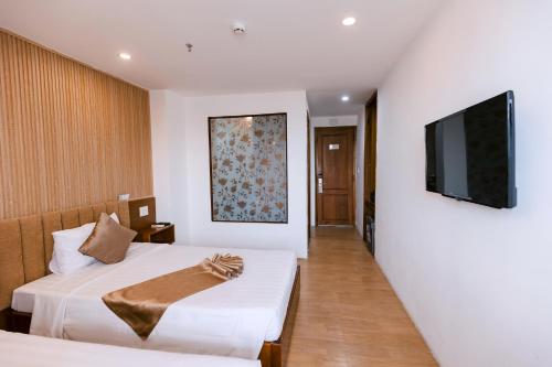 a hotel room with two beds and a flat screen tv at Gardenia Hue Hotel in Hue