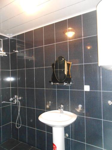a black tiled bathroom with a sink and a mirror at Mziuri Guest House in Mestia