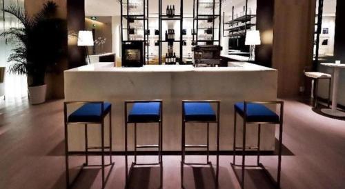a bar with four blue stools in a room at Jinjiang Metropolo Shanghai Xujiahui Nanhuating Hotel in Shanghai