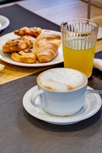 una taza de café y un plato de pan y un vaso de jugo de naranja en Palazzo Belvedere Chianciano Terme, en Chianciano Terme