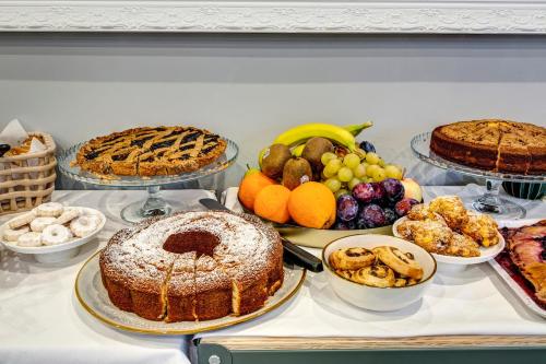 Una mesa llena de diferentes tipos de pasteles y otros alimentos. en Palazzo Belvedere Chianciano Terme, en Chianciano Terme