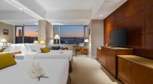 a hotel room with two beds and a flat screen tv at Kai Wah Plaza International Hotel in Kunming