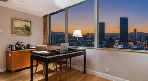 a desk with a laptop on it in a room with a window at Kai Wah Plaza International Hotel in Kunming